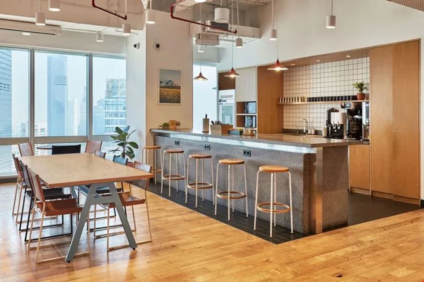 Modern coworking space with open seating, a sleek kitchen area, and city views in Jakarta.