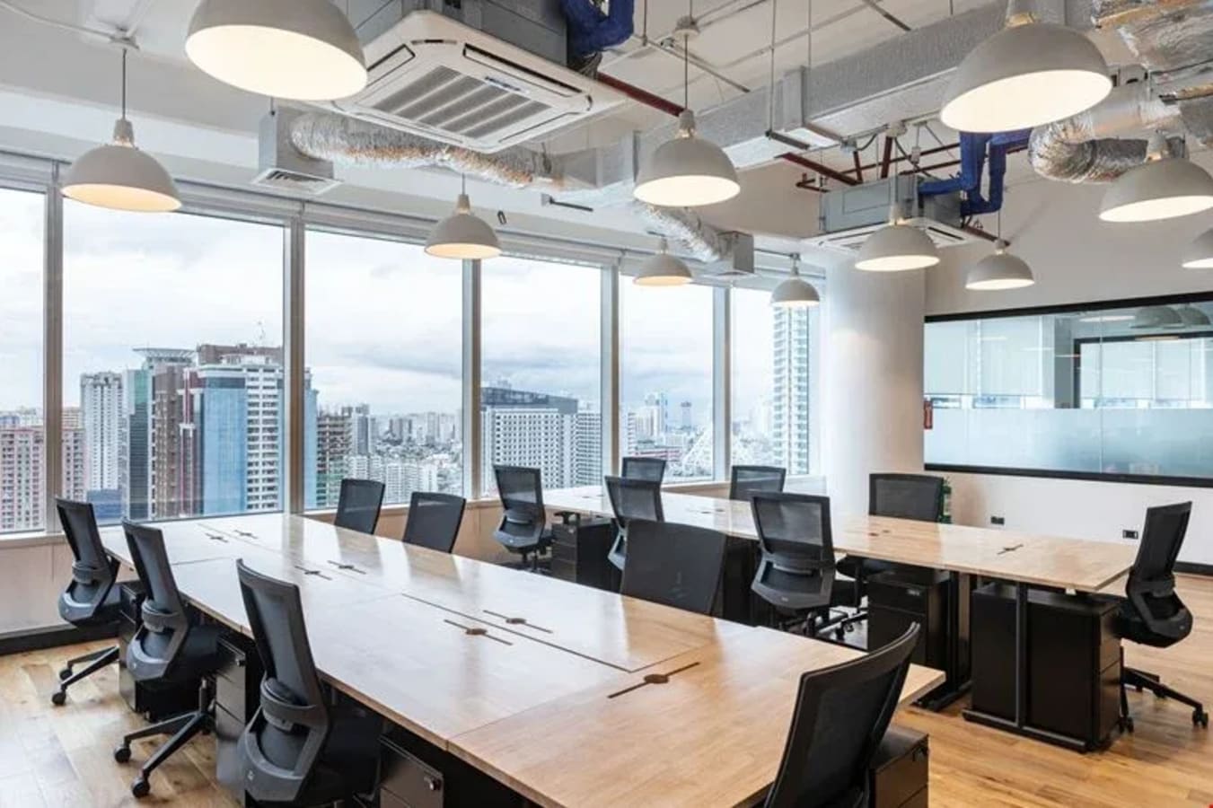 Modern coworking space with large windows, ergonomic chairs, and natural light on Ayala Avenue.