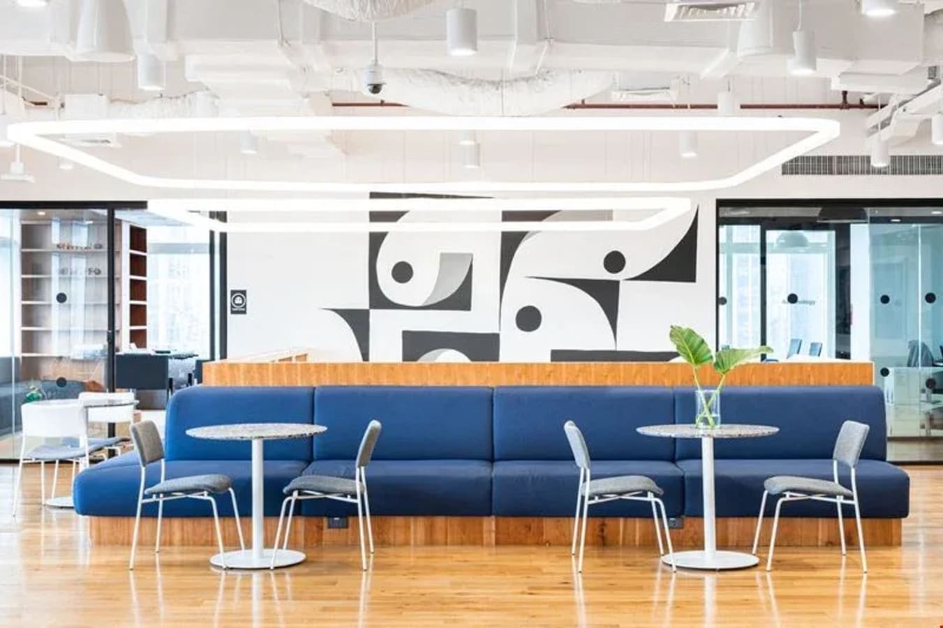 Modern coworking area with vibrant blue seating, sleek tables, and abundant natural light.