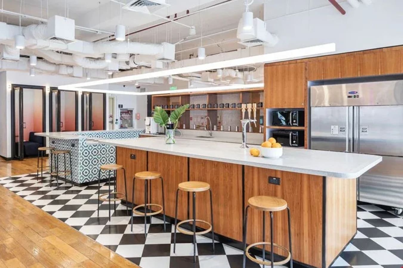 Modern coworking space with stylish kitchen area, ample seating, and vibrant design accents.