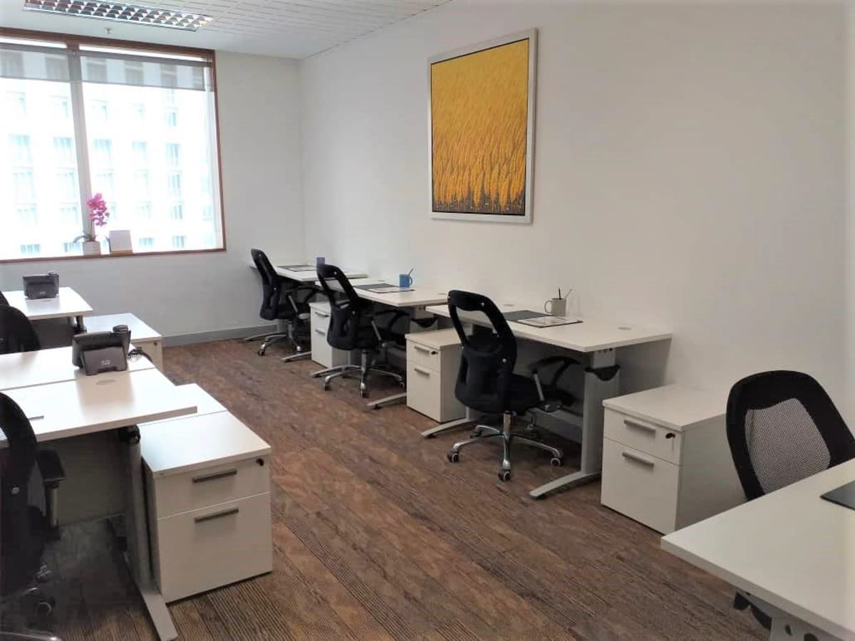 Bright coworking space with modern desks and ergonomic chairs, featuring ample natural light.