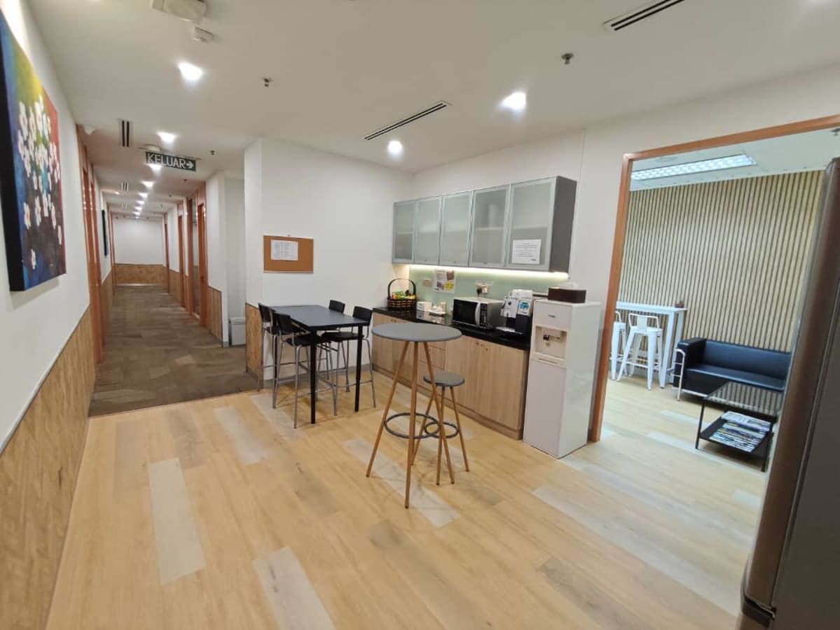 Modern coworking space with a kitchenette, lounge seating, and ample natural light in Jalan Pinang.