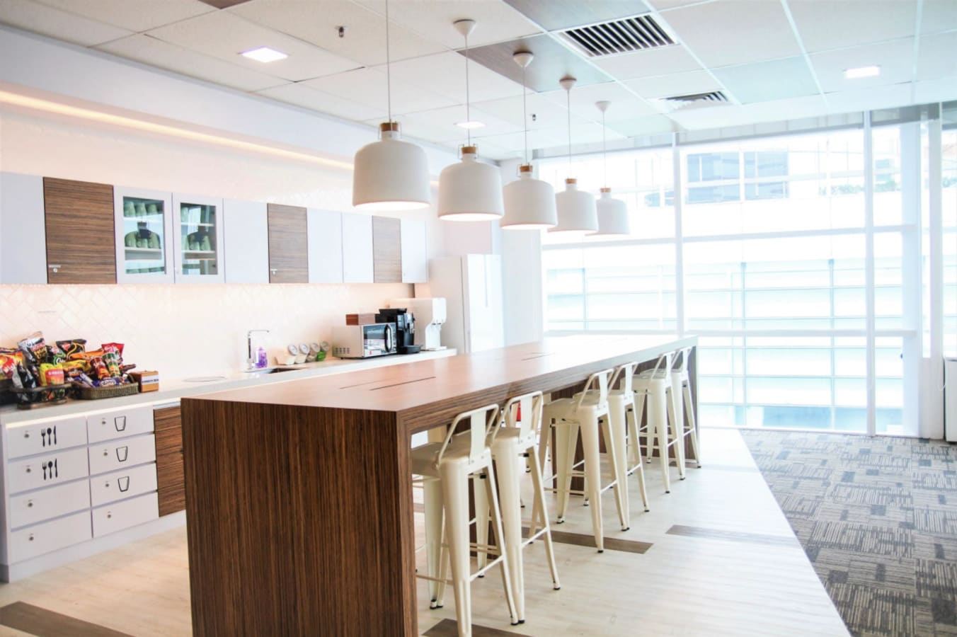 Modern coworking space with a sleek kitchen area and abundant natural light. Ideal for collaboration.