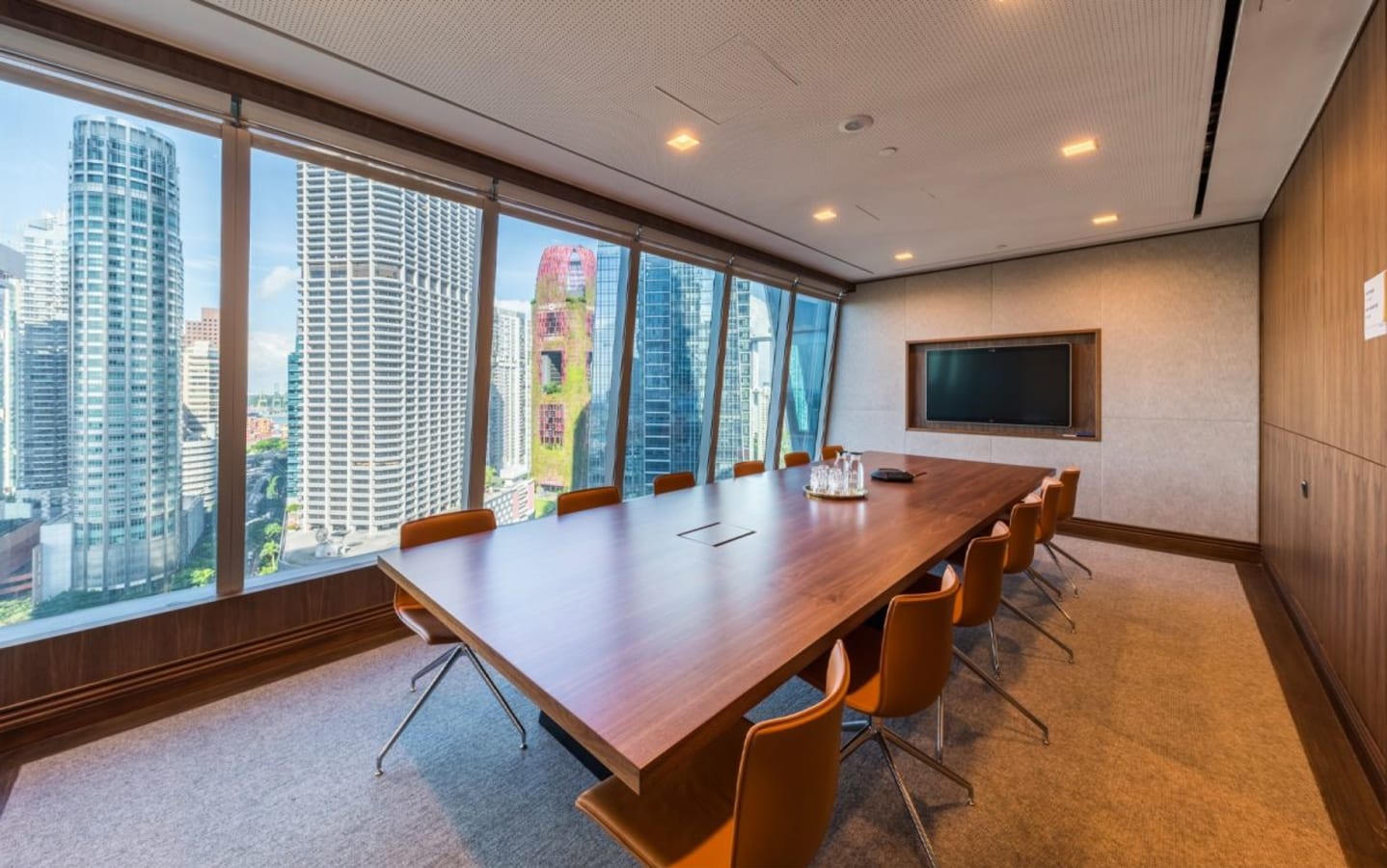 Modern conference room with skyline views, sleek wooden table, and comfortable seating.