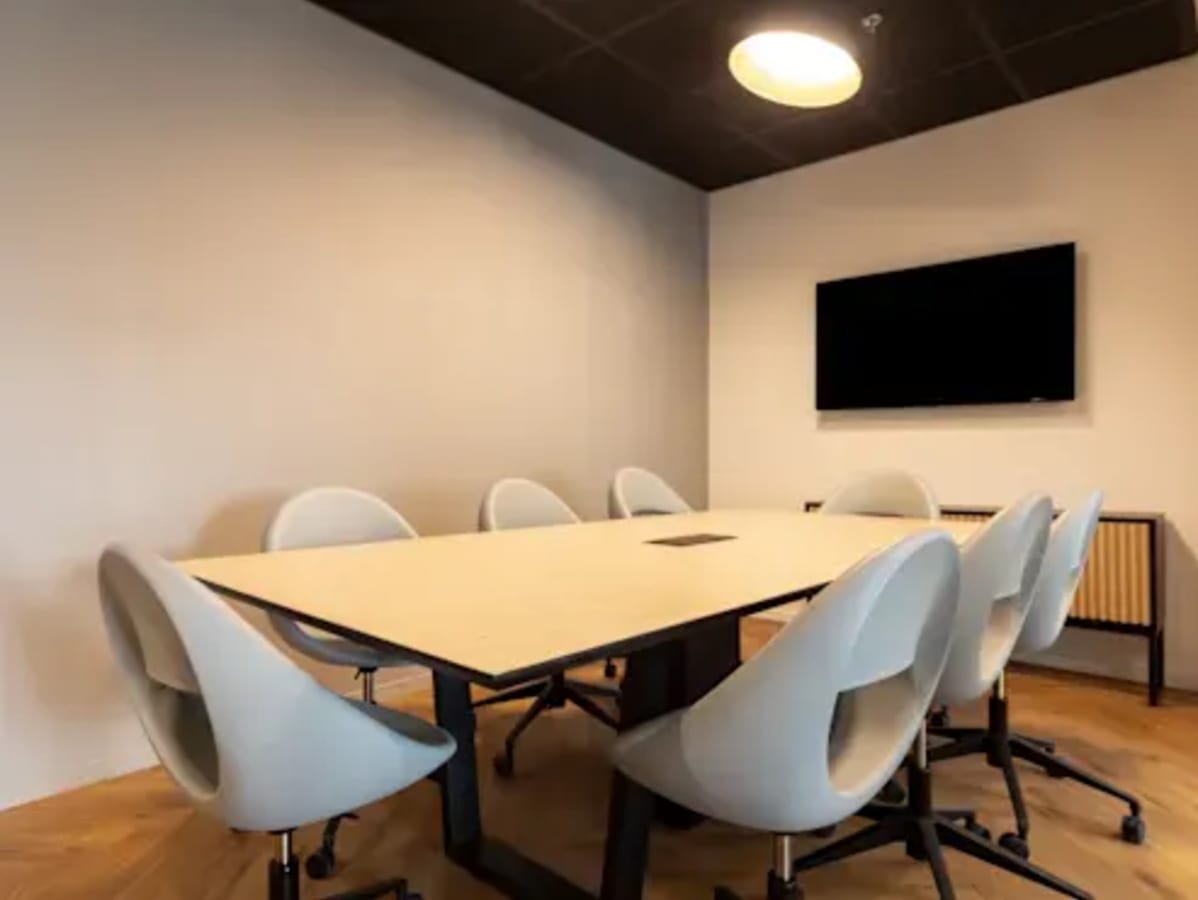 Sleek meeting room with modern seating and a large screen, perfect for collaborative sessions.