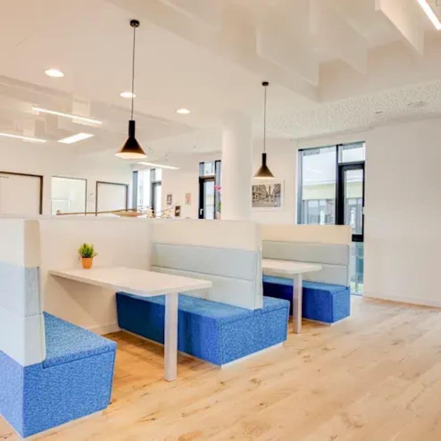Bright, modern coworking space with cozy booth seating and stylish pendant lighting.
