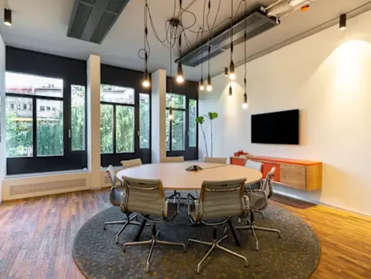 Modern coworking space with stylish round table, ergonomic chairs, and ample natural light.