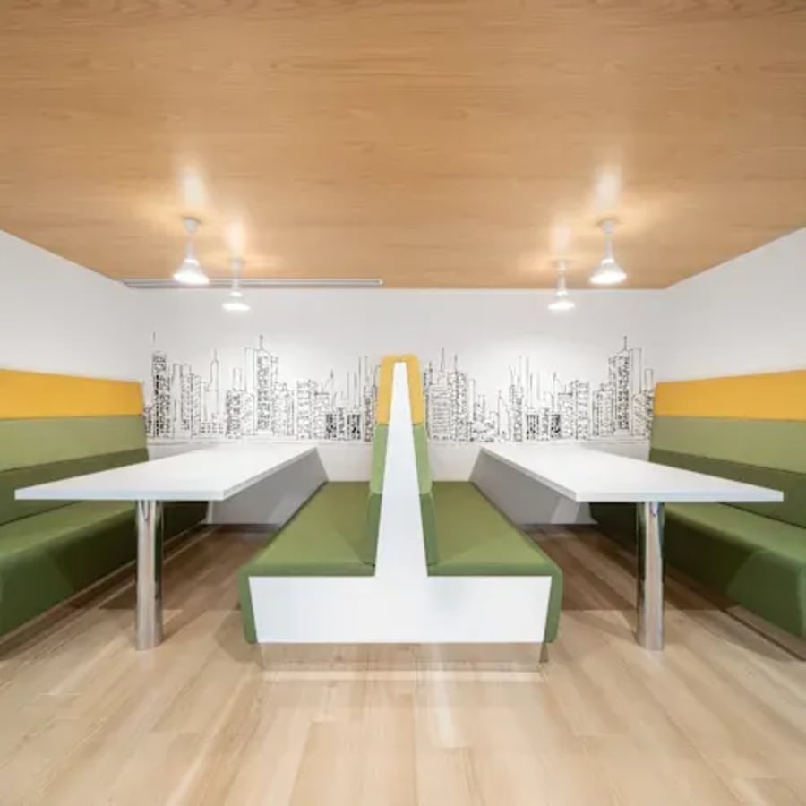 Contemporary coworking area with city-themed decor, plush seating, and ample natural light.