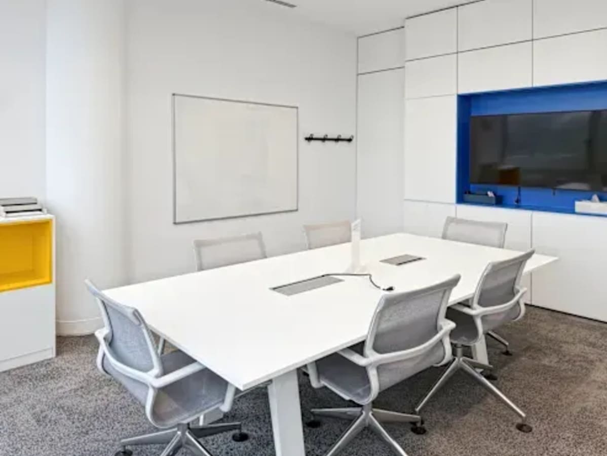 Modern meeting room with sleek white decor, ample seating, and a digital screen in a Manila coworking space.