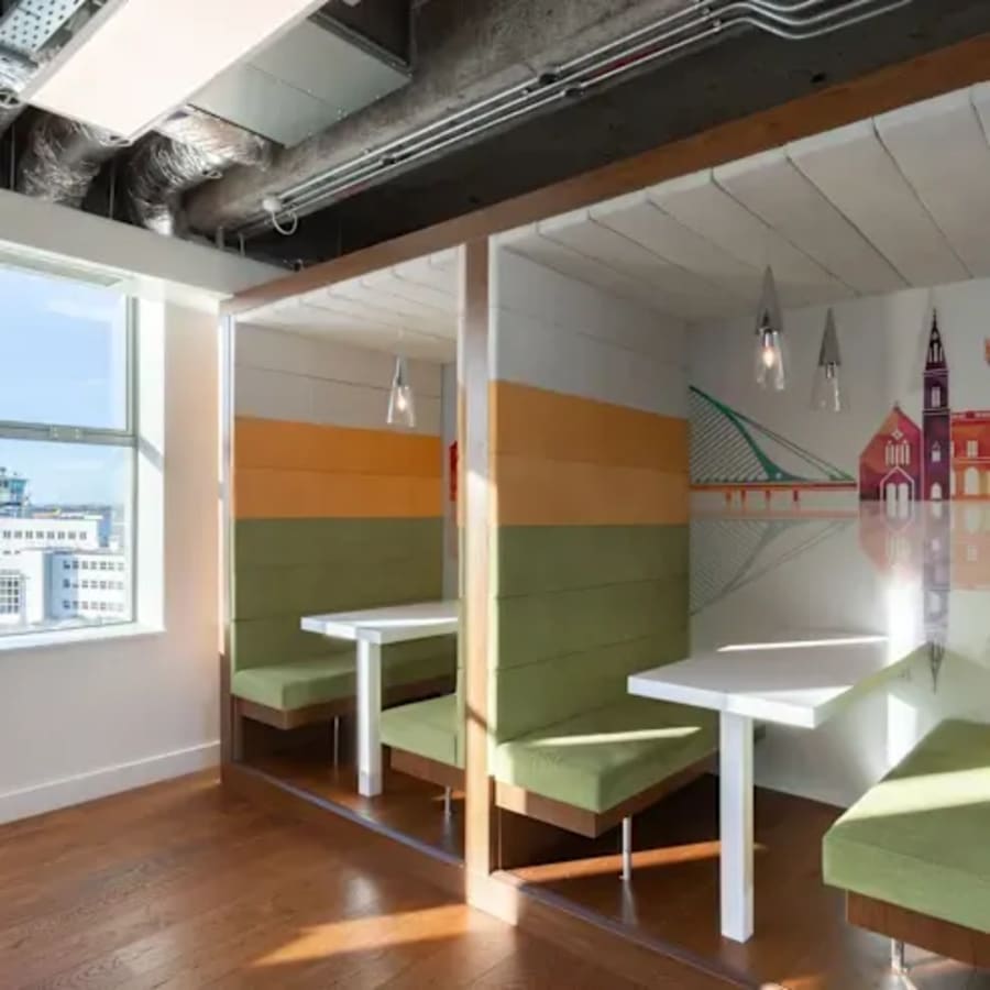 Colorful booths with city-themed decor and ample natural light in a flexible coworking space.