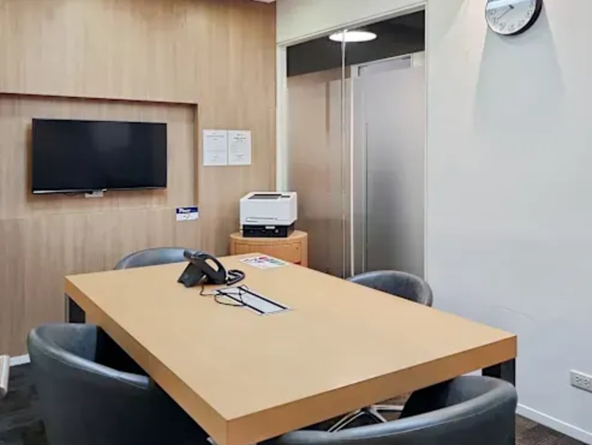 Modern meeting room with a sleek table, comfortable chairs, and a wall-mounted TV in Mabalacat coworking space.