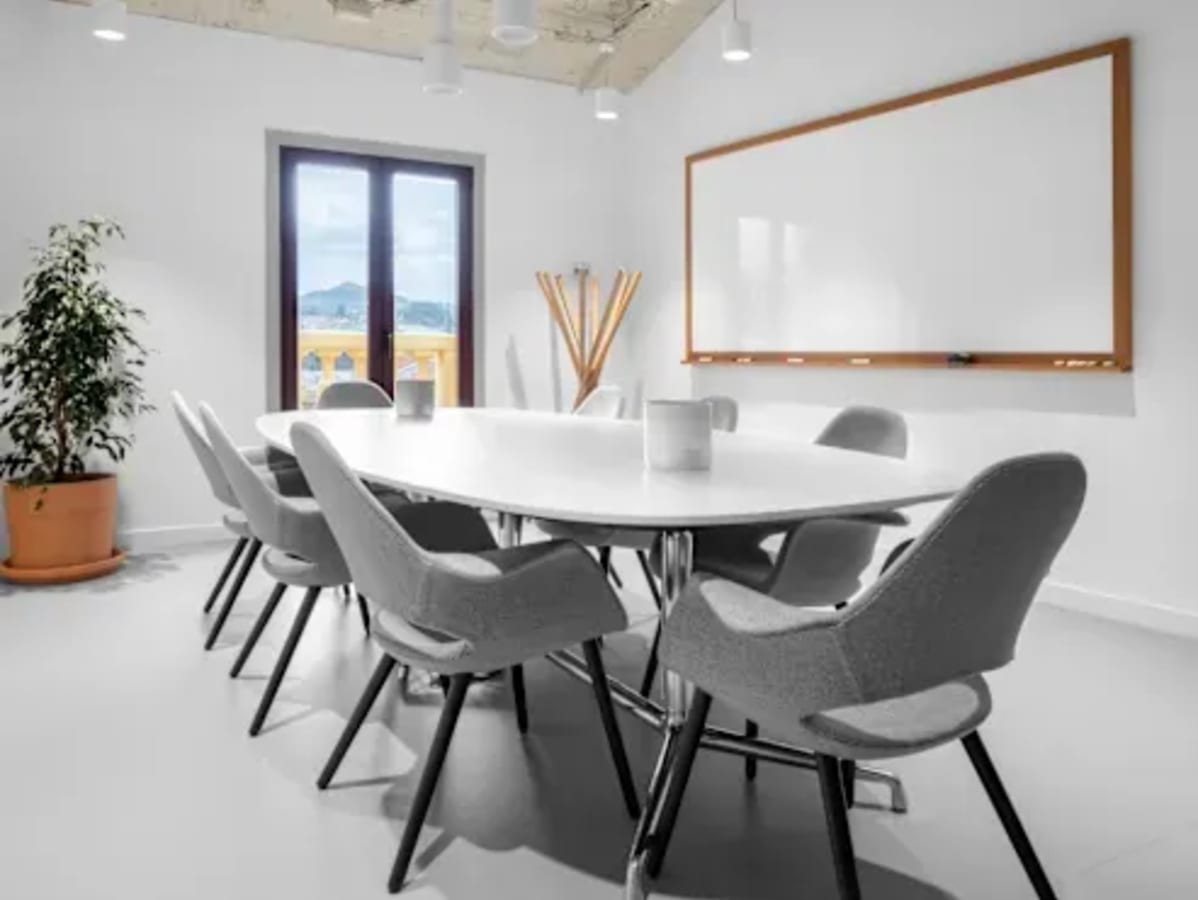 Bright, modern meeting room with natural light and a whiteboard, perfect for collaboration.