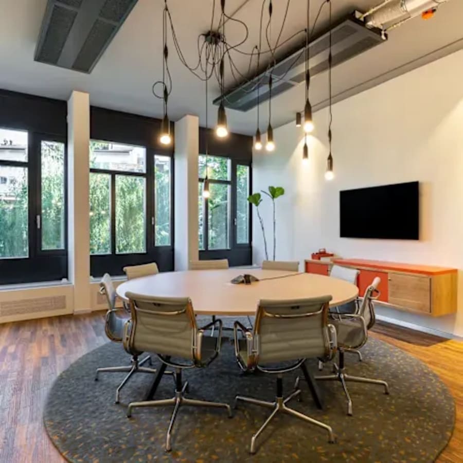 Modern coworking space with stylish lighting, natural light, and a collaborative round table setup.