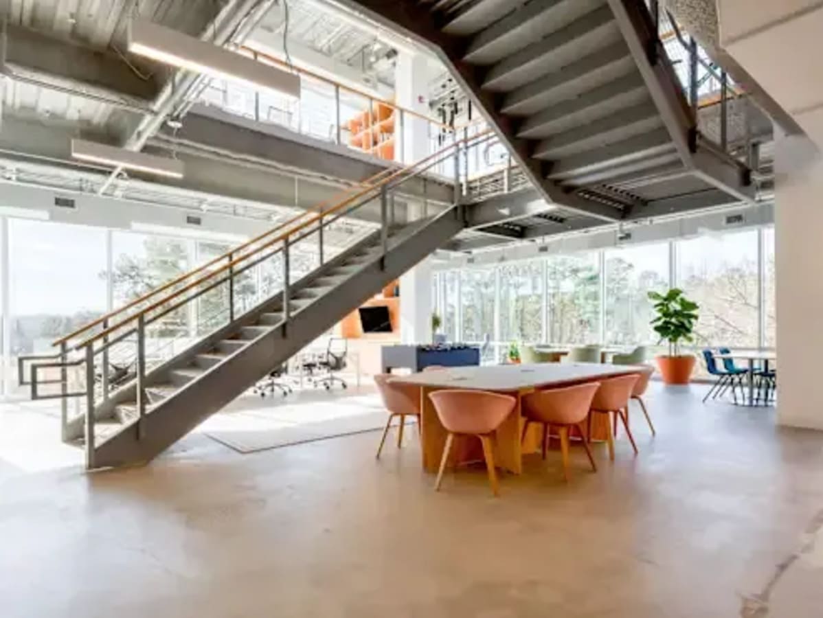 Bright coworking space with modern design, featuring open seating, natural light, and lush views.