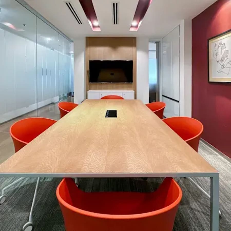 Modern meeting room with vibrant red chairs, sleek table, and glass partitions on Ayala Avenue.