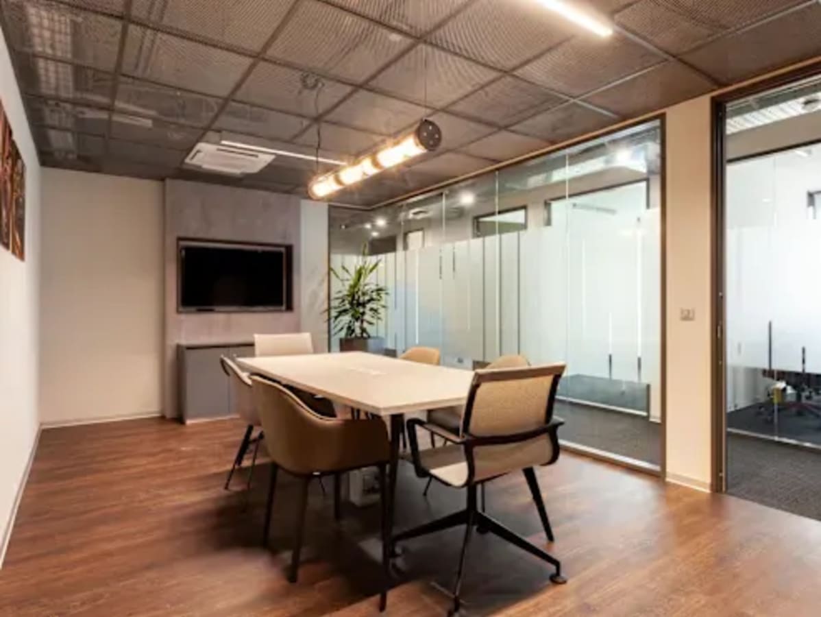 Modern meeting room with sleek glass walls, elegant lighting, and comfortable seating.