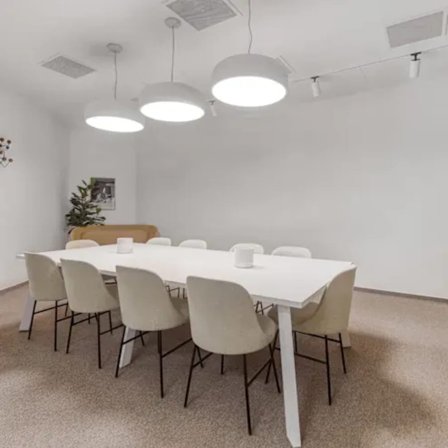 Modern coworking space featuring a sleek conference table, ample seating, and soft lighting.