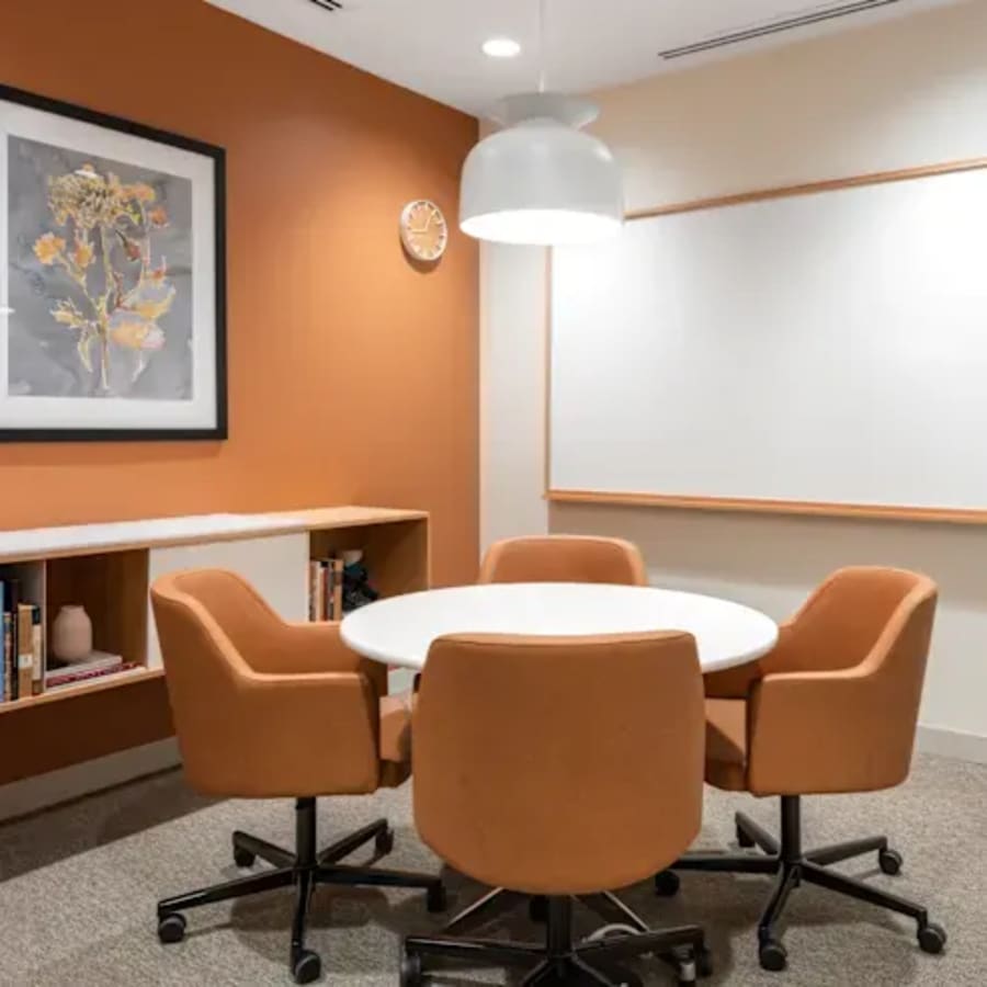 Modern meeting room with comfortable chairs, art, and a whiteboard in Vadodara coworking space.