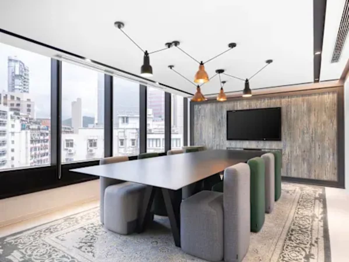 Modern conference room with city views, stylish lighting, and a large screen for presentations.