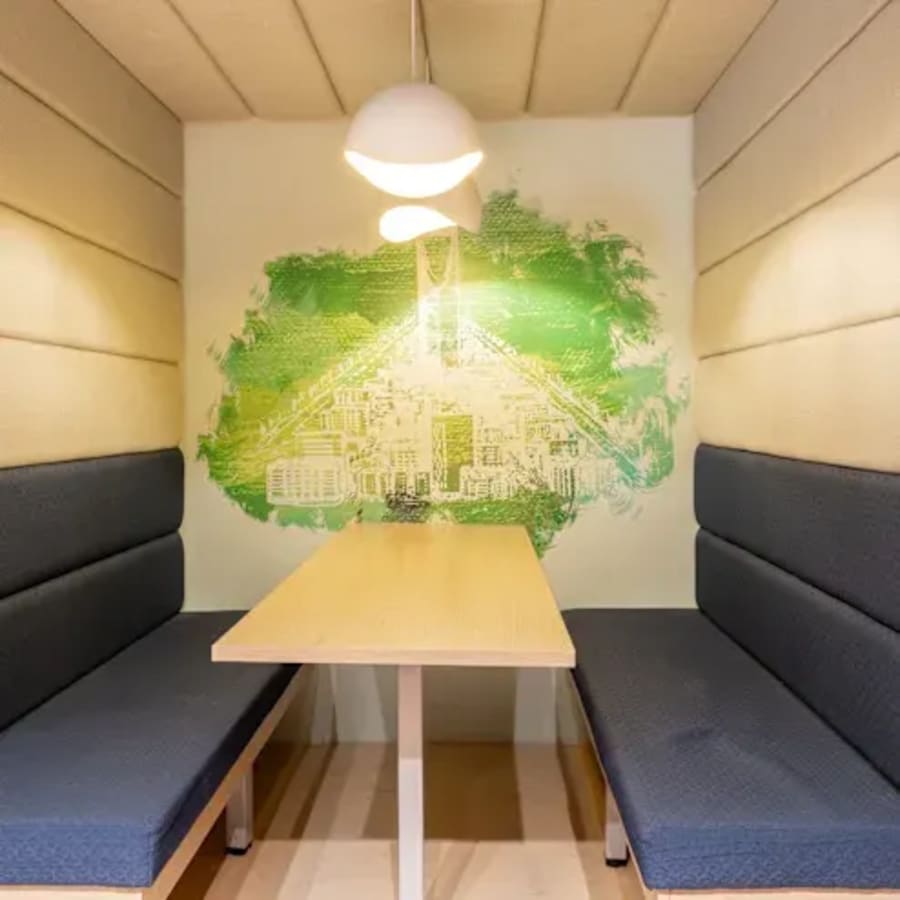 Cozy booth with modern lighting and vibrant mural, perfect for collaboration.