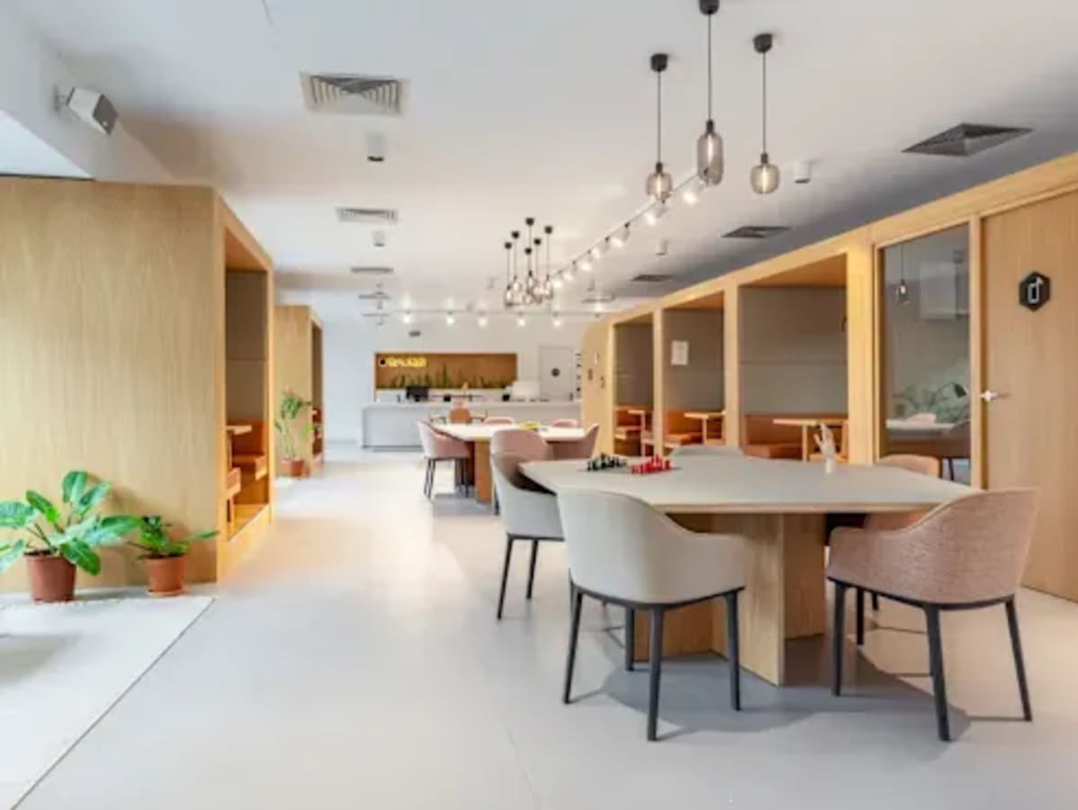 Modern coworking space in Vadodara with private booths, communal tables, and stylish lighting.