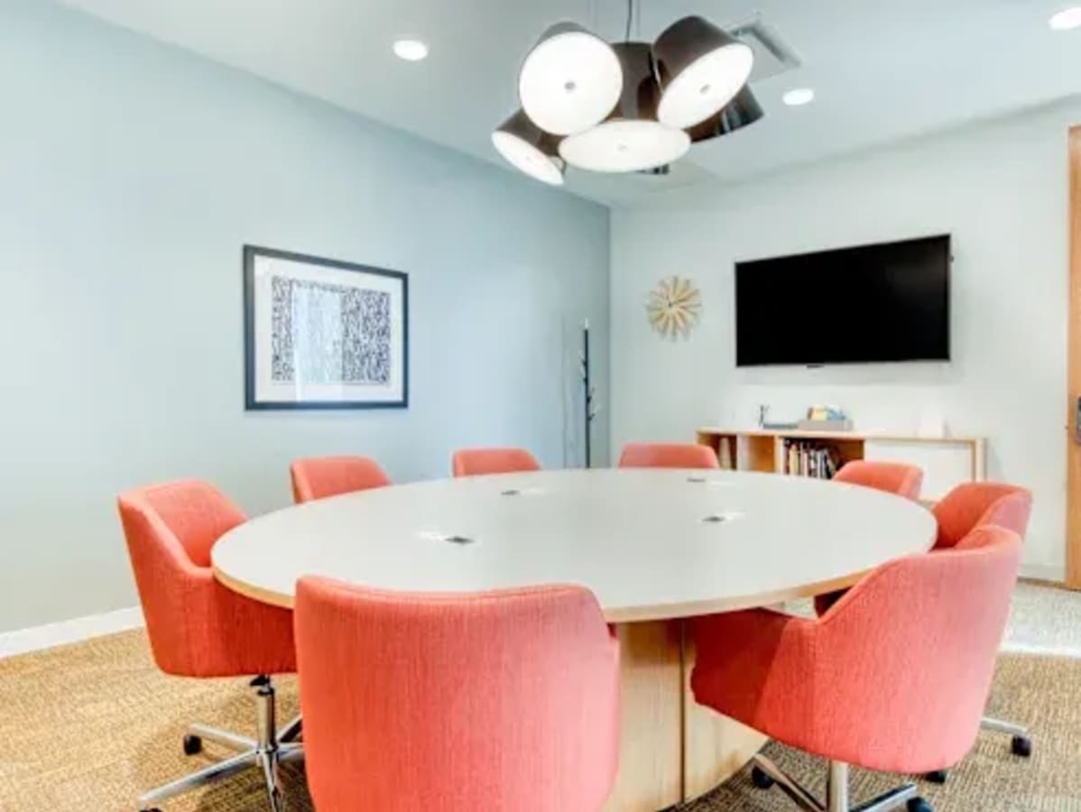 Modern conference room with bright seating, wall art, and TV, perfect for collaborative meetings.
