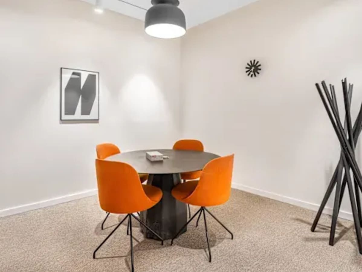 Modern coworking meeting area with vibrant orange chairs and sleek decor in Hyderabad.