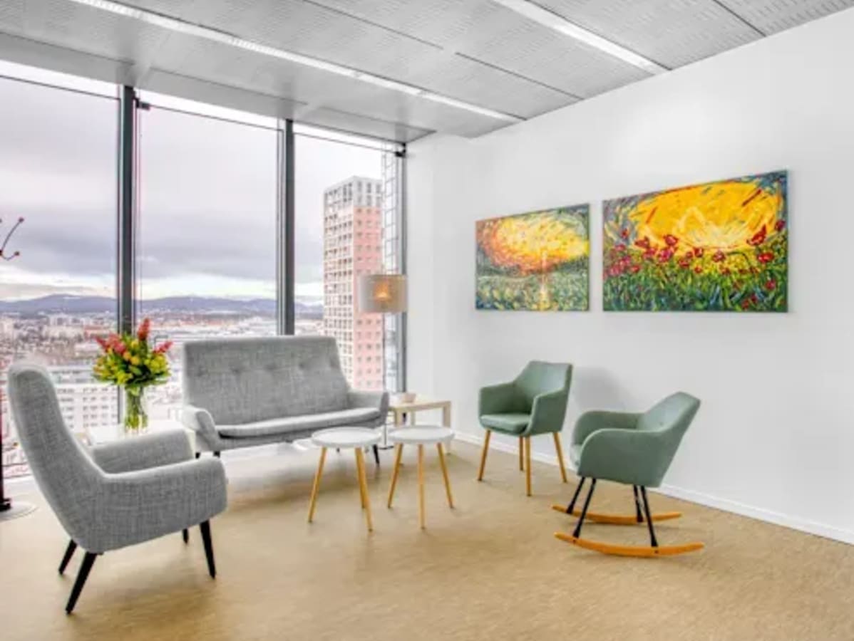 Bright, modern office with city views, stylish seating, and vibrant art. Perfect for collaboration.