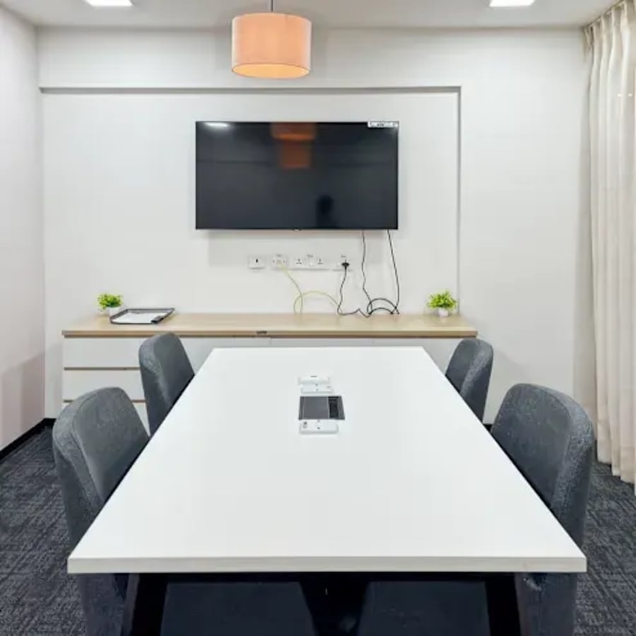 Modern meeting room with a sleek table, comfortable chairs, and a large screen for presentations.