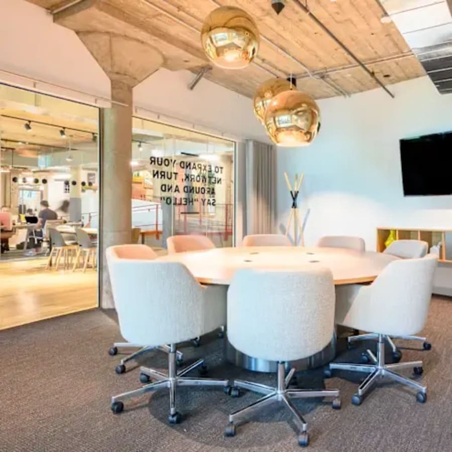 Modern coworking area with round table, plush chairs, and warm lighting on Ambli - Bopal Road.