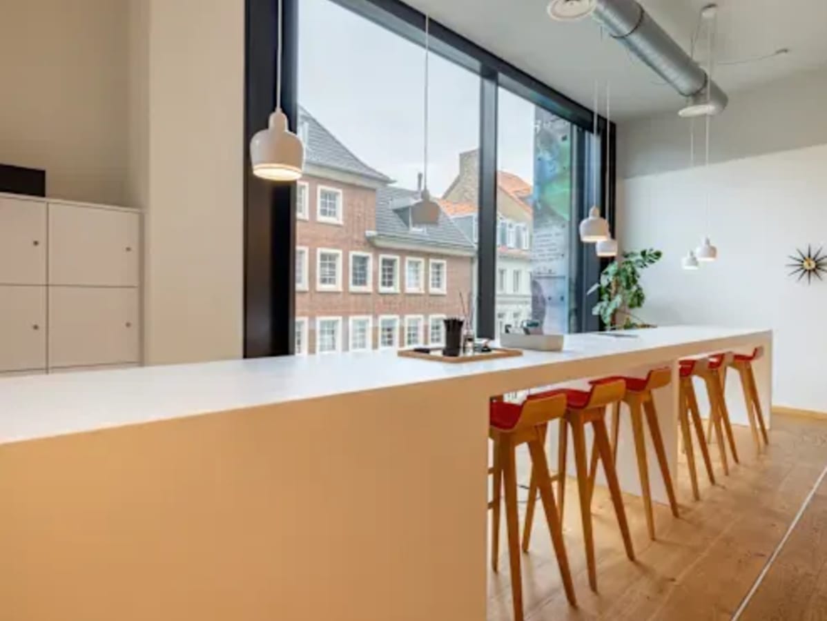 Modern coworking area with high seating, abundant natural light, and sleek pendant lighting.