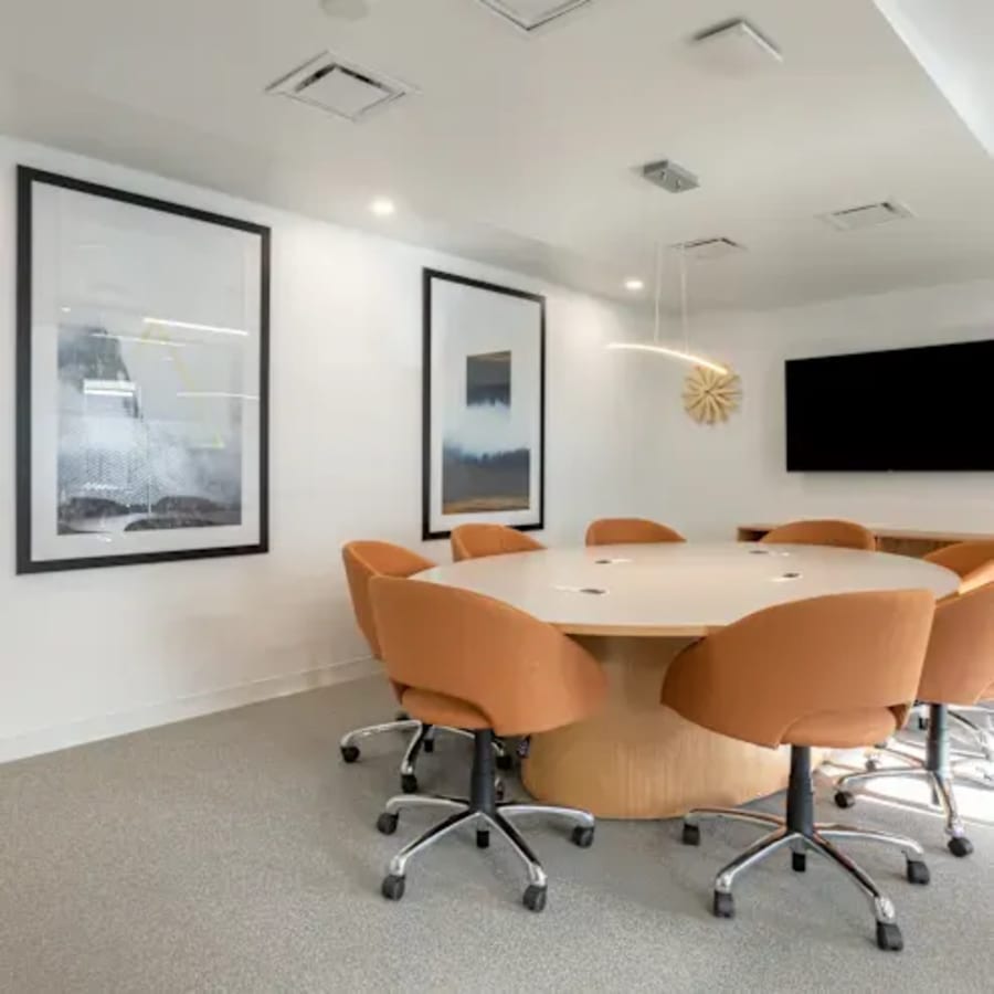 Modern meeting room with ergonomic chairs, sleek table, and dynamic artwork for creative collaboration.