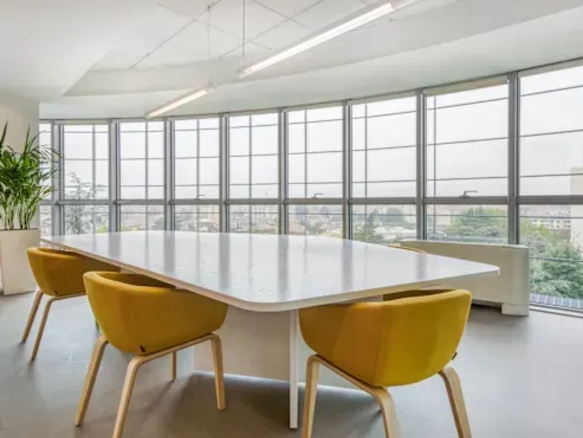Bright coworking space with large windows, modern table, and vibrant seating on White Field Road.
