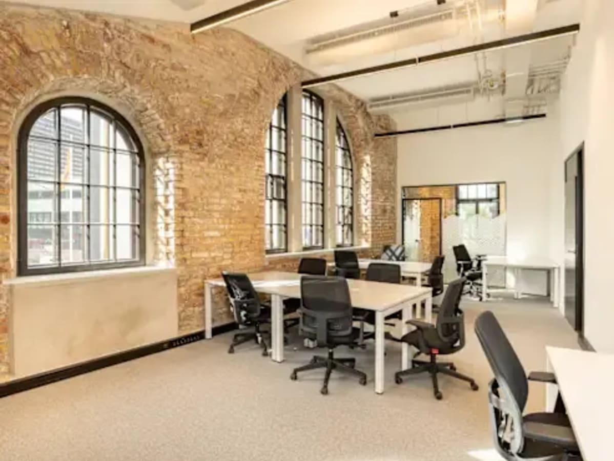 Open, airy coworking space with natural light, exposed brick, and modern furnishings.