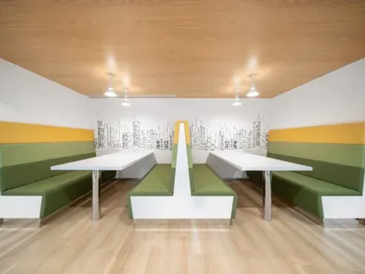 Modern coworking space in Vadodara with vibrant booth seating and skyline artwork.