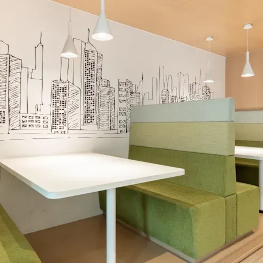 Modern coworking space with cozy booth seating and artistic cityscape wall art.