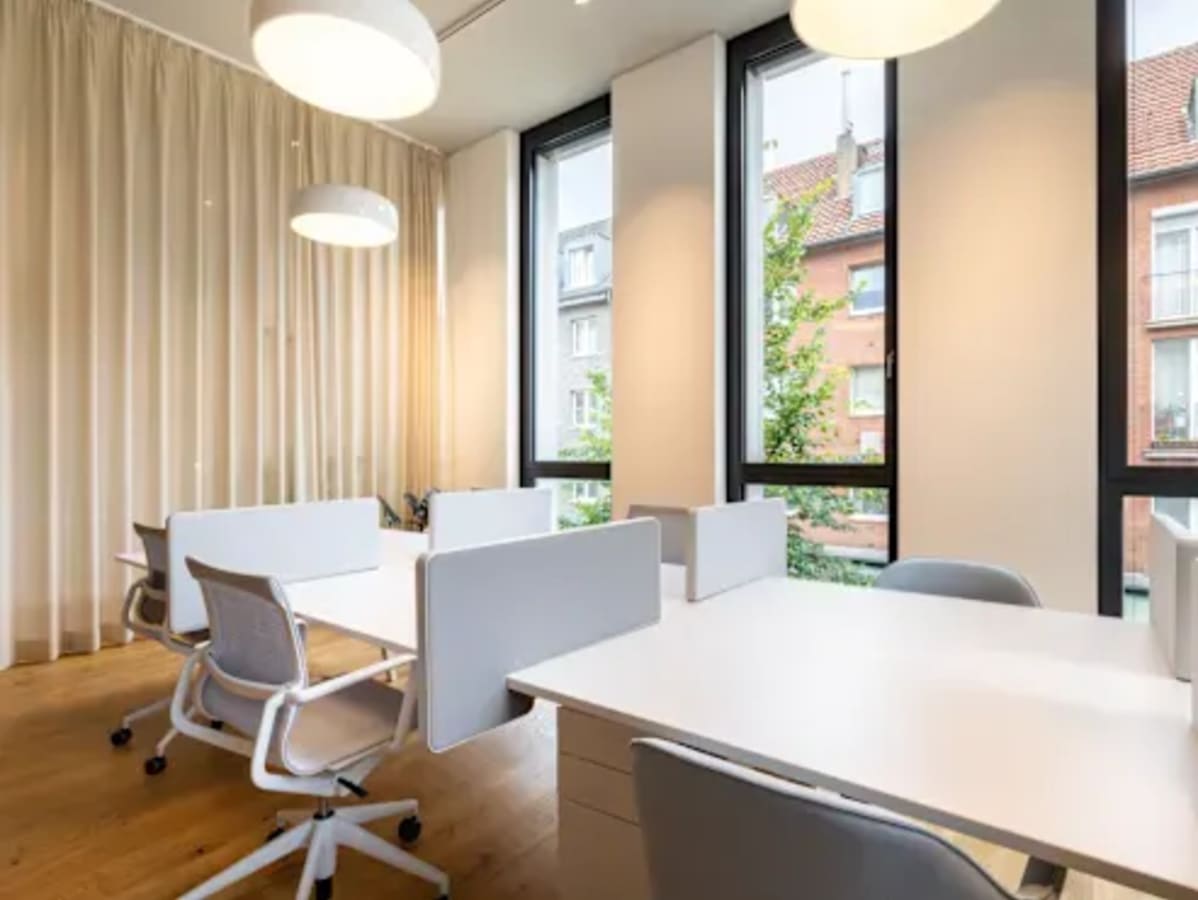 Bright coworking space with modern desks, ergonomic chairs, and large windows for natural light.