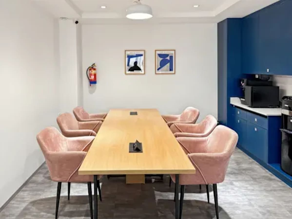 Modern meeting room with plush seating, sleek wooden table, and vibrant blue cabinetry.