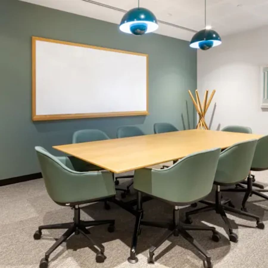 Modern meeting room with a long table, comfortable chairs, and stylish lighting. Ideal for collaboration.
