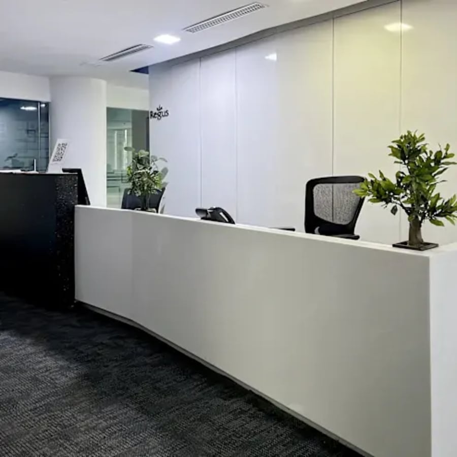 Modern reception area with sleek desks, ergonomic chairs, and vibrant greenery. Ideal for coworking.