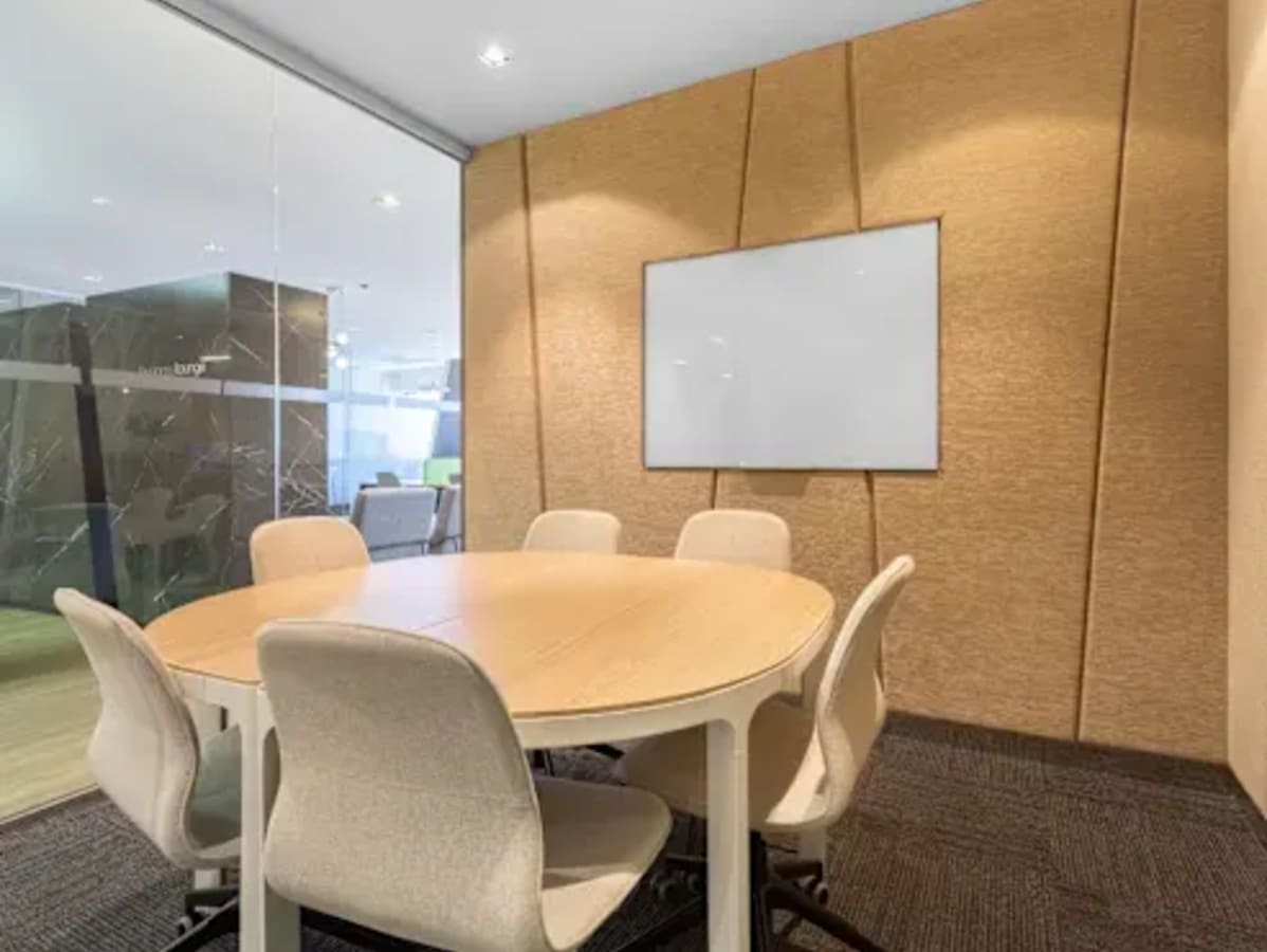Modern meeting room with a round table, whiteboard, and contemporary chairs. Ideal for collaboration.