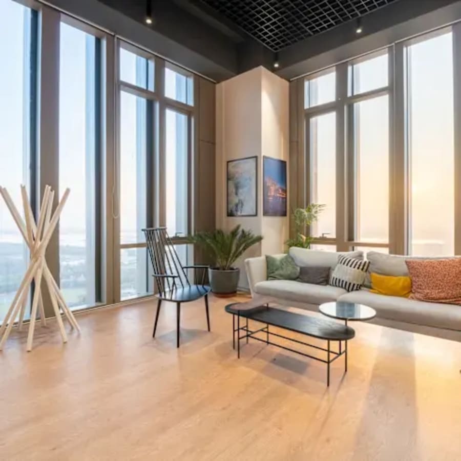 Bright, modern coworking space with high ceilings, cozy seating, and expansive windows.