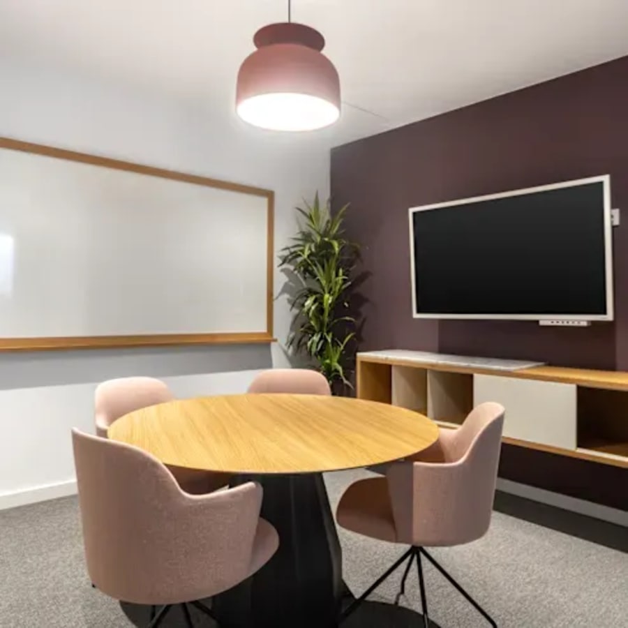Modern meeting area with cozy seating, a whiteboard, and a TV for presentations.