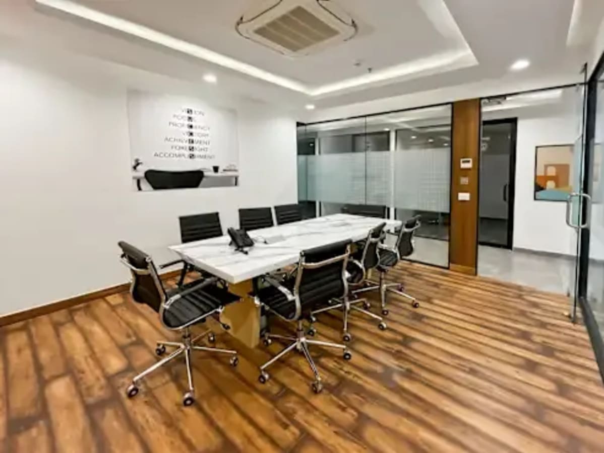 Sleek, modern conference room with wooden flooring and glass walls in a coworking space.