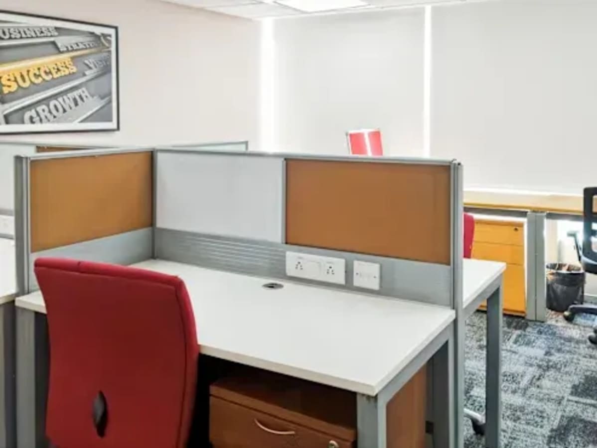 Modern coworking space with ergonomic chairs, partitioned desks, and ample natural lighting.