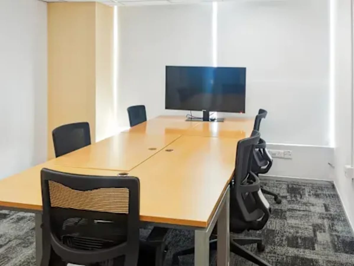 Modern meeting room in Jaipur with ergonomic chairs, a wooden table, and a large screen.