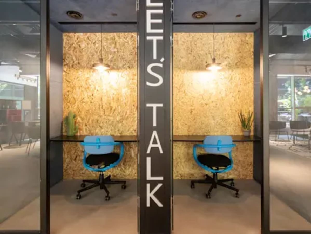 Contemporary coworking booths with vibrant seating and ample lighting, ideal for focused work.