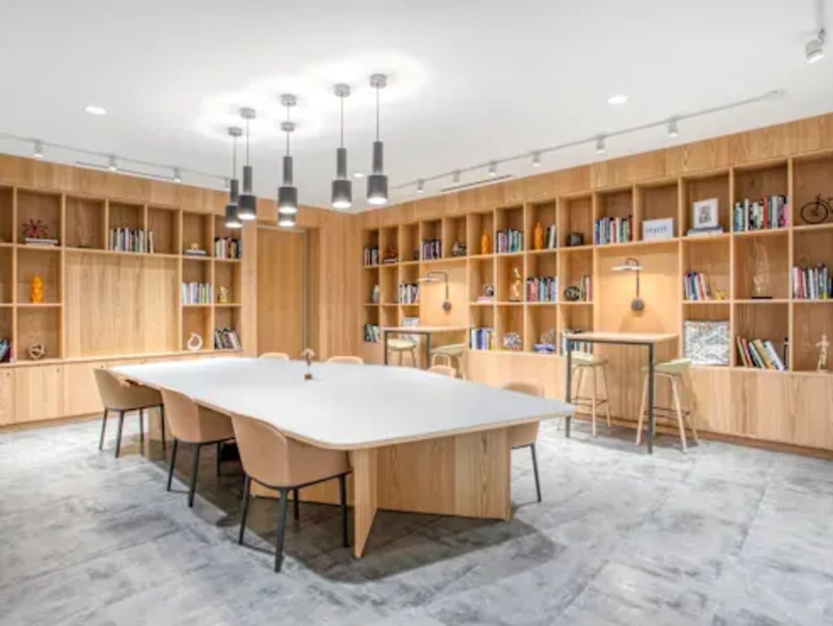 Bright and inviting coworking space with modern furnishings and ample shelving.