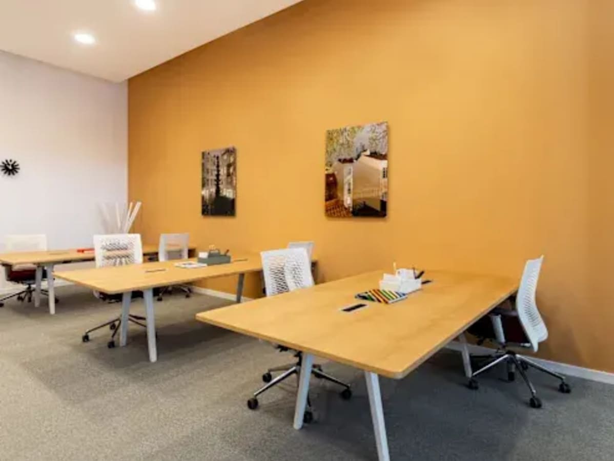 Bright coworking space with modern desks, ergonomic chairs, and vibrant wall art.