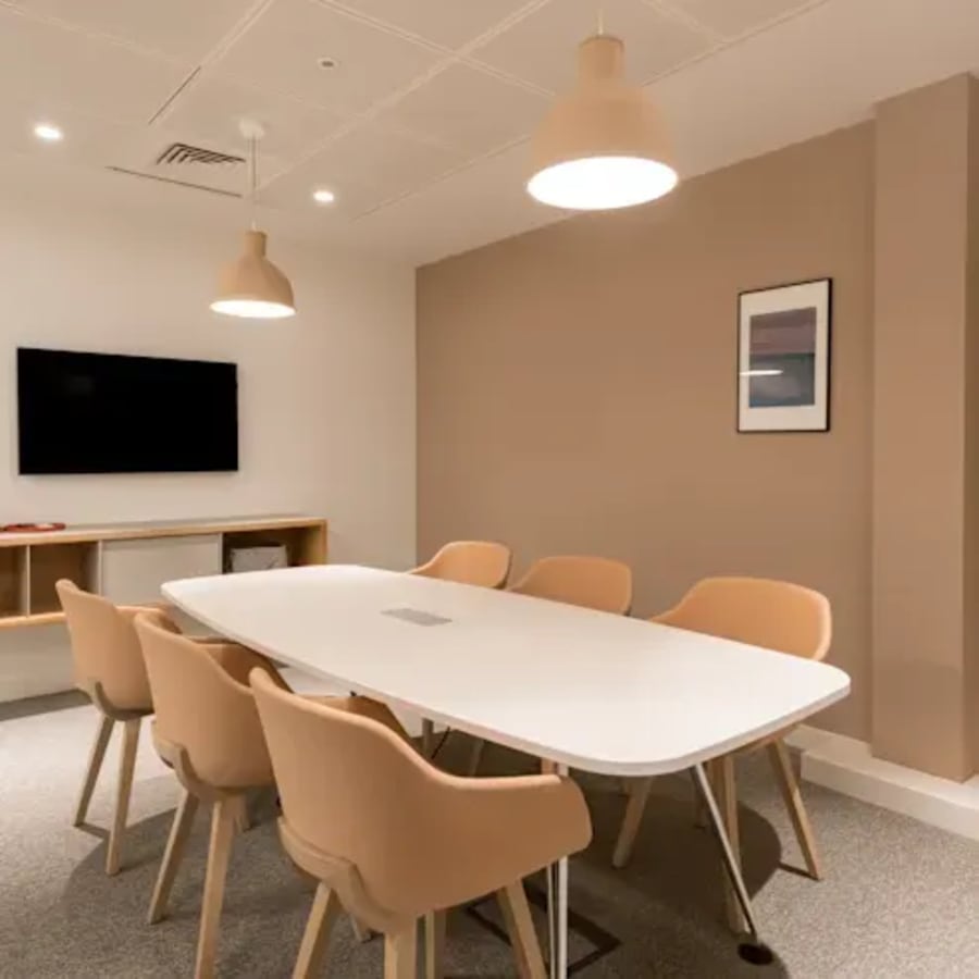 Modern coworking space with a sleek table, ergonomic chairs, and soft lighting. Ideal for collaboration.